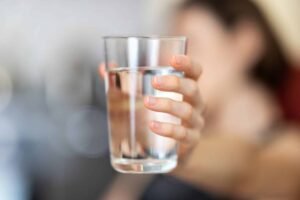 Close-up of hand holding a clear glass of water