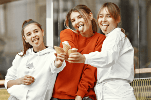 Three young women smiling and holding ice cream cones outside