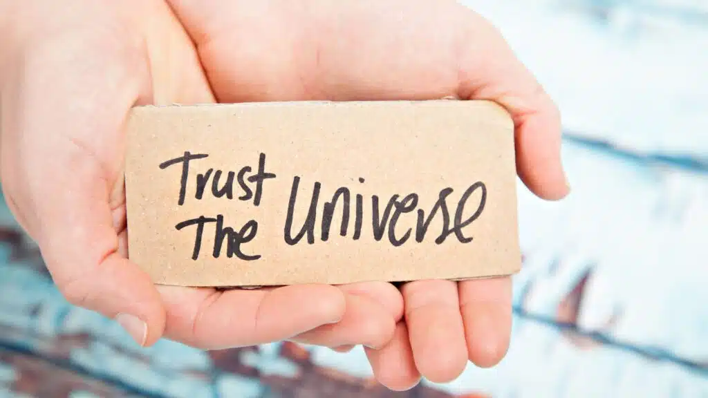 Hands holding a sign with Trust the Universe message