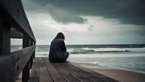 Person sitting on boardwalk overlooking stormy ocean waves