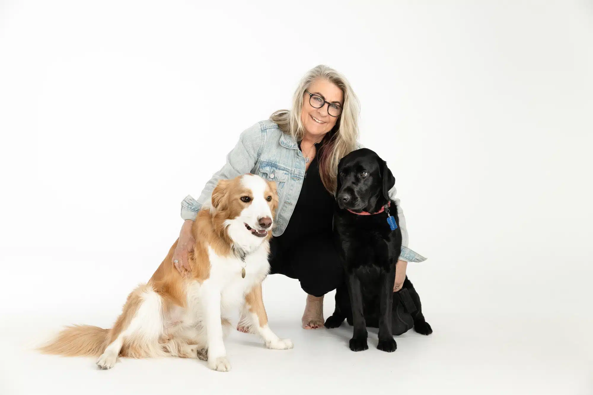 Smiling woman with two dogs posing in a studio setting