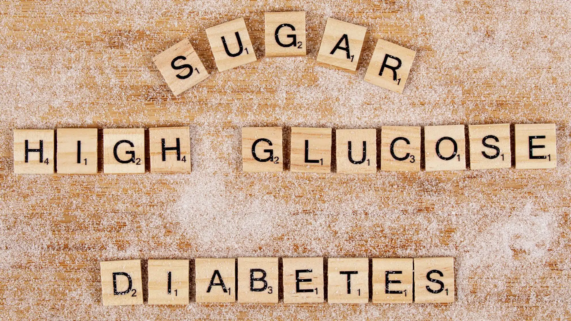 Scrabble tiles spelling sugar, high glucose, diabetes on sugared surface
