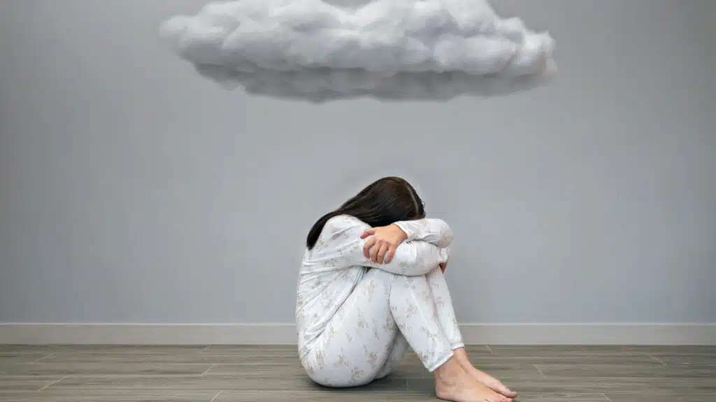 Person in pajamas sitting on floor under a cloud-shaped object