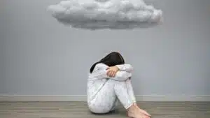 Person in pajamas sitting on floor under a cloud-shaped object