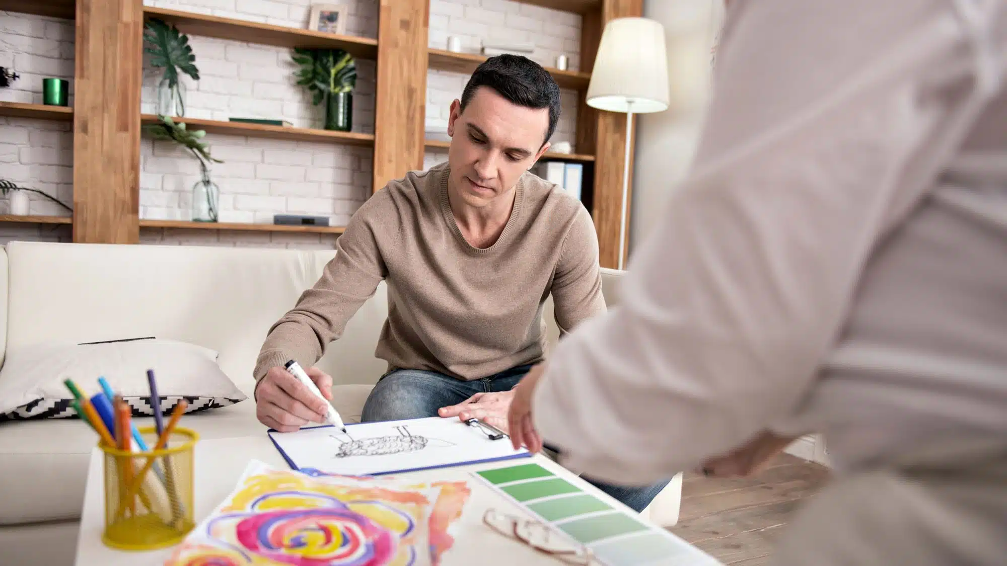 Man sketching interior design concept with materials and colour samples
