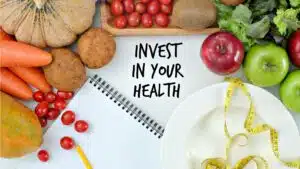 Healthy foods and a notebook with 'Invest in Your Health' message