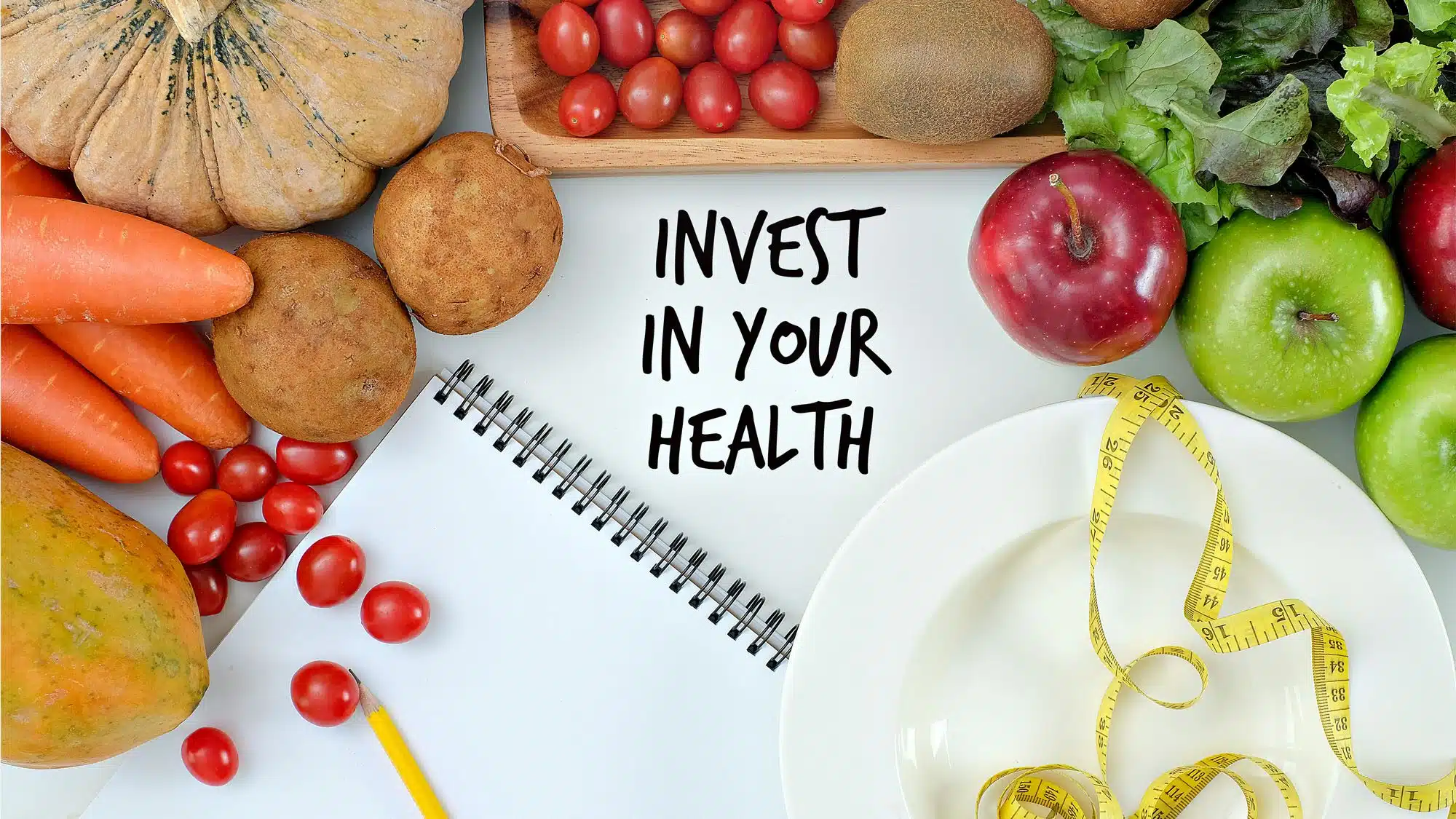 Healthy foods and a notebook with 'Invest in Your Health' message