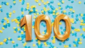 Gold number 100 candles on blue background with yellow and blue confetti