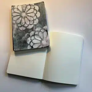 Two notebooks, one closed with floral design, one open on blank pages