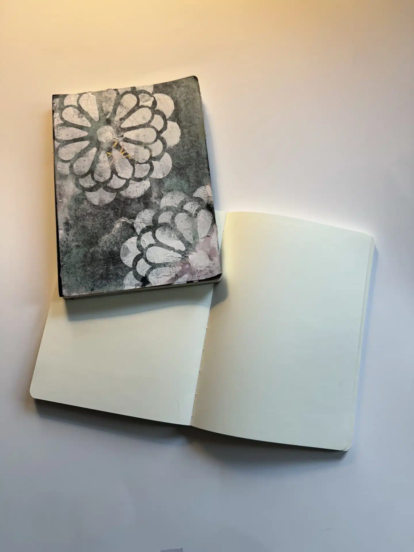 Two notebooks, one closed with floral design, one open on blank pages