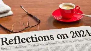 Newspaper headlines 'Reflections on 2024' with coffee and glasses