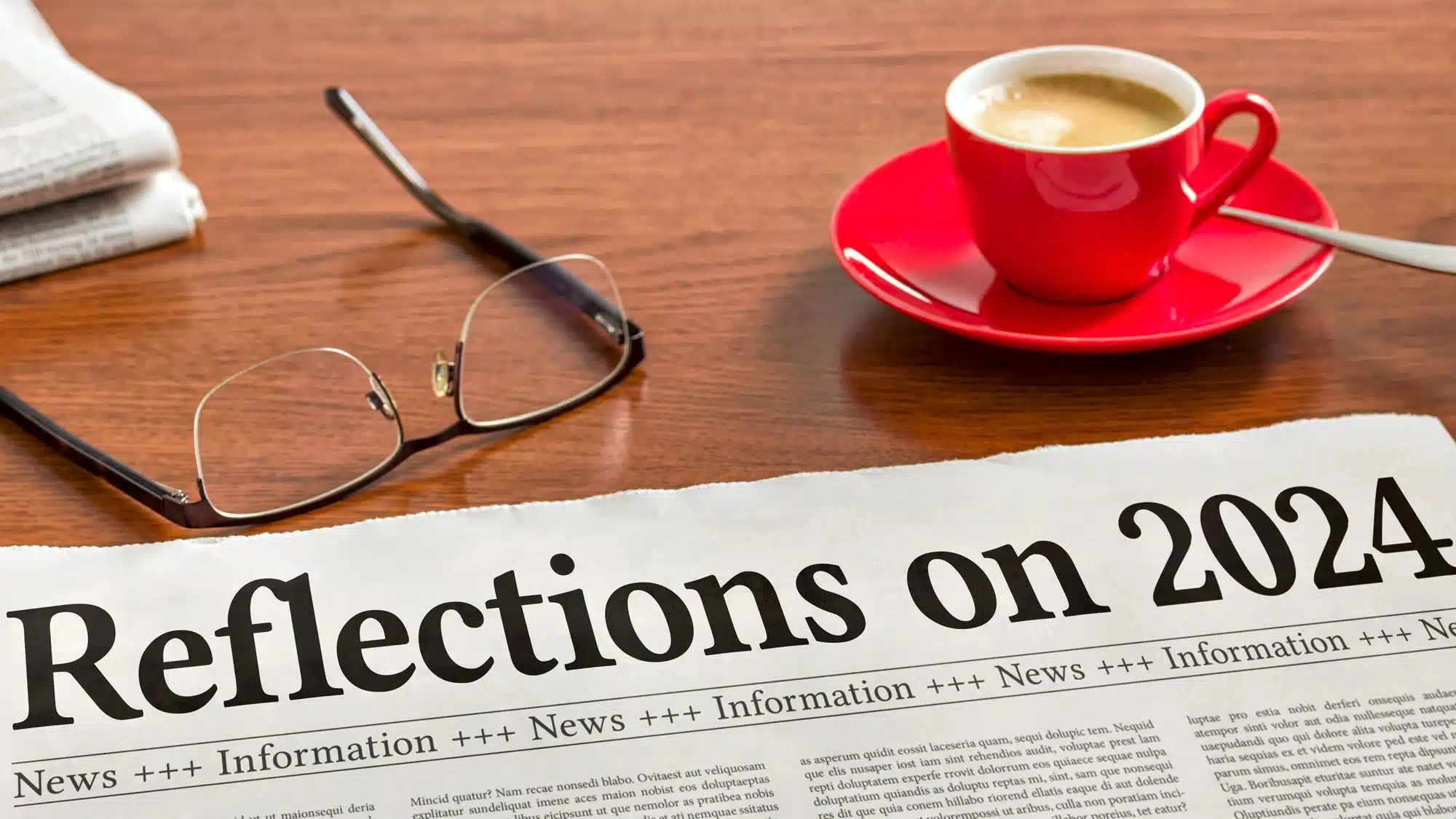 Newspaper headlines 'Reflections on 2024' with coffee and glasses