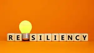 Concept image of resiliency with glowing lightbulb and wooden blocks