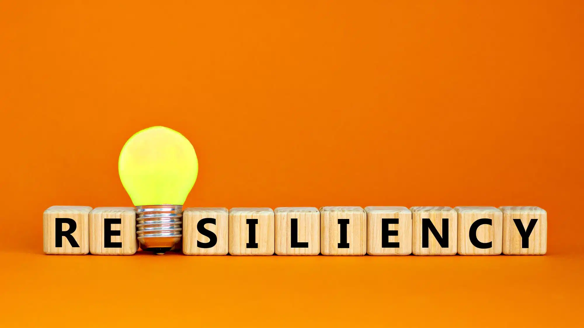 Concept image of resiliency with glowing lightbulb and wooden blocks