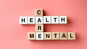 Scrabble letters forming mental health care on pink paper