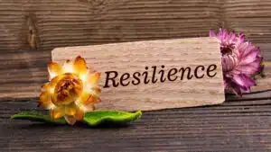Wooden sign with 'Resilience' and flowers, symbolizing strength and growth
