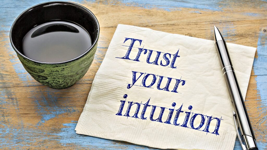 Coffee cup with pen and napkin saying Trust your intuition