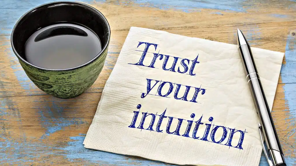 Coffee cup with pen and napkin saying Trust your intuition