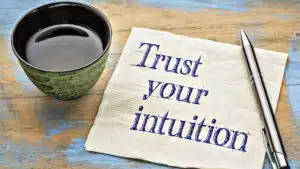 Coffee cup with pen and napkin saying Trust your intuition