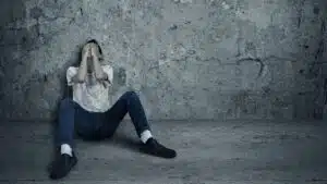 Person sitting in despair against a concrete wall