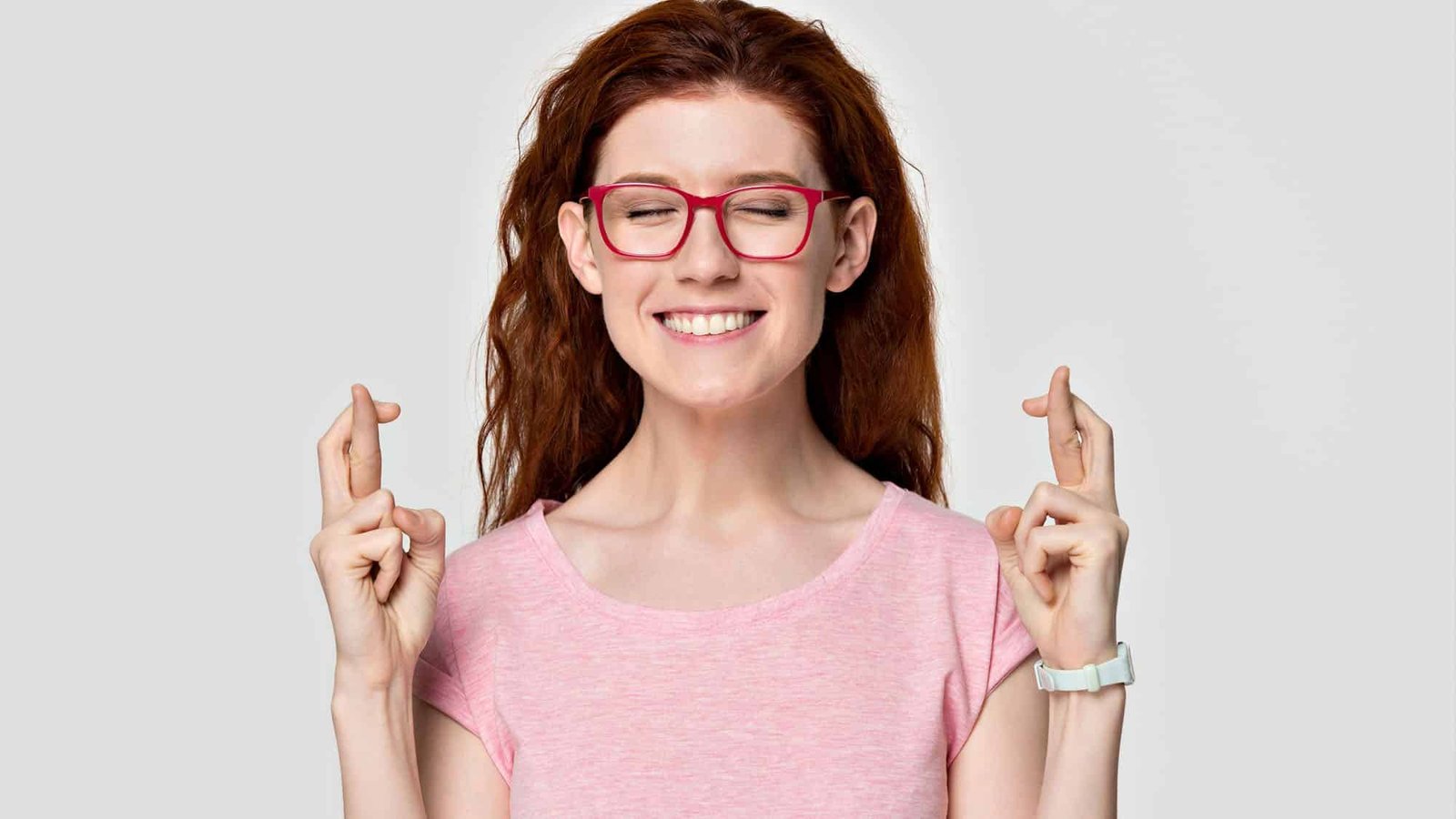 Woman with red glasses, fingers crossed, smiling