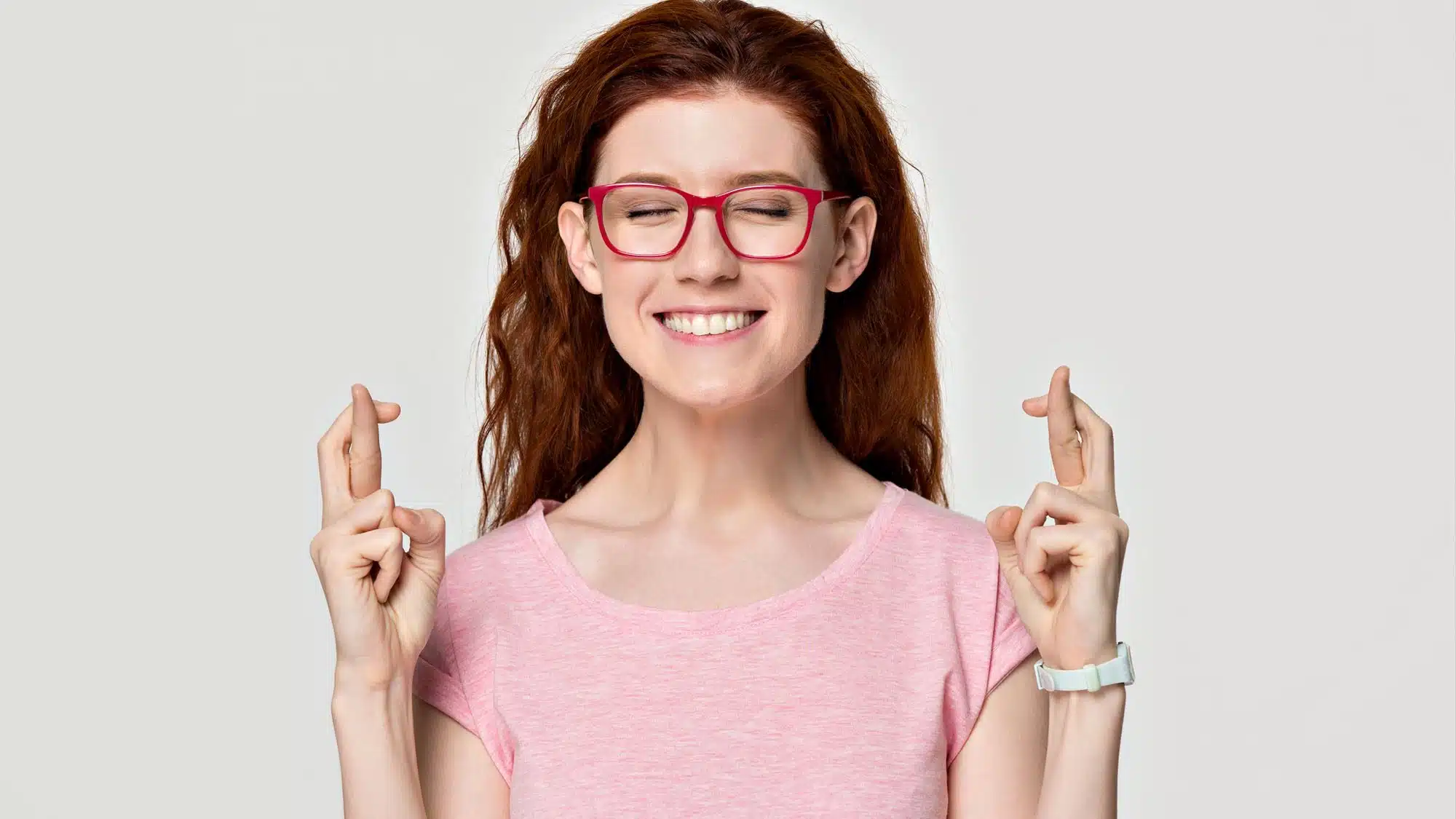 Woman with red glasses, fingers crossed, smiling
