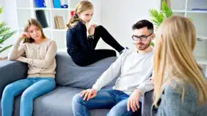 Young adults engaged in group therapy session on grey sofa