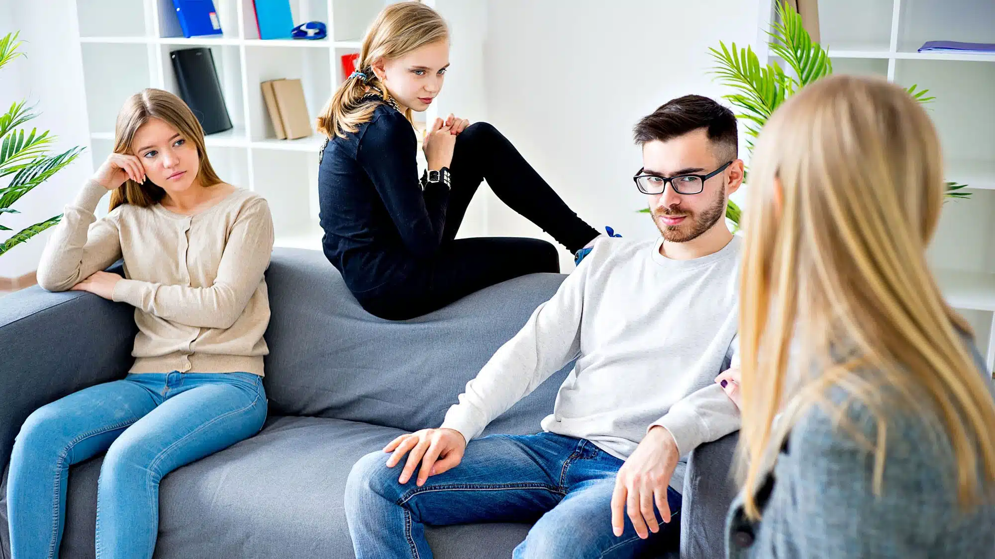 Young adults engaged in group therapy session on grey sofa