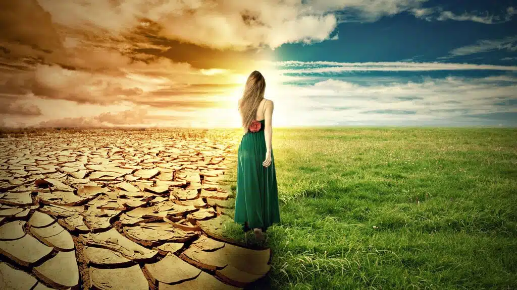 Woman walking from barren land to lush field under dynamic sky