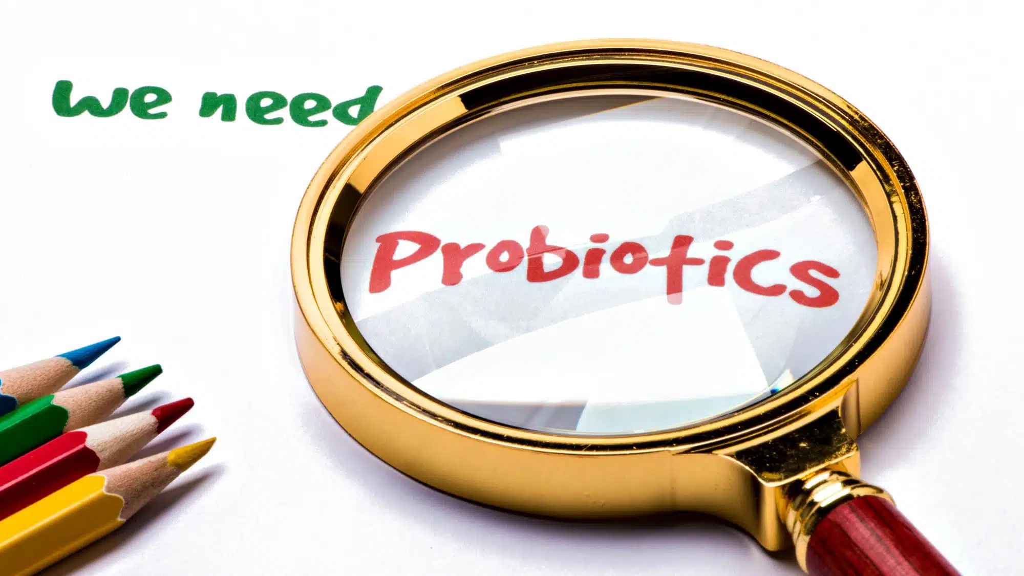Magnifying glass over the word probiotics with colourful pencils nearby