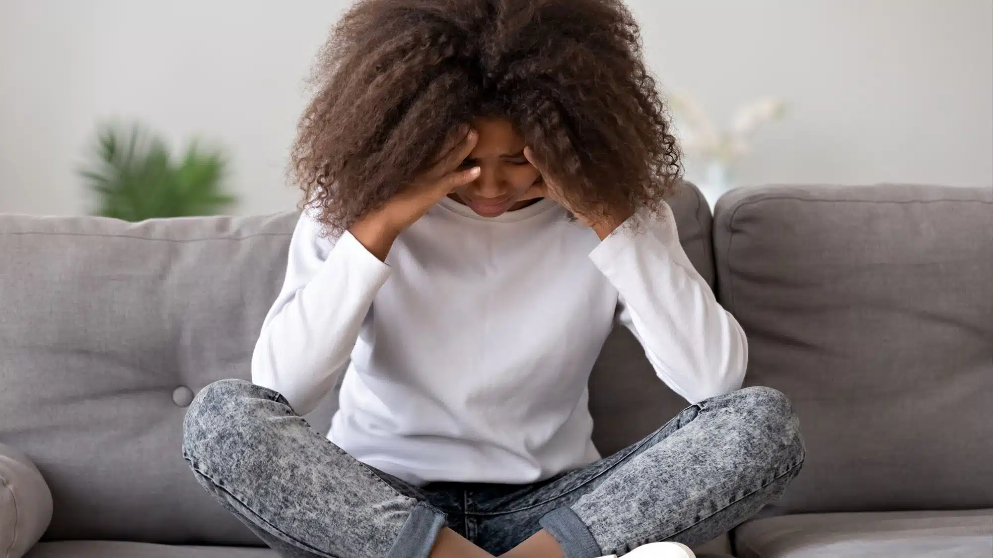 Woman with curly hair stressed on a couch
