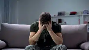 Man in distress sitting on a couch in a dimly lit room
