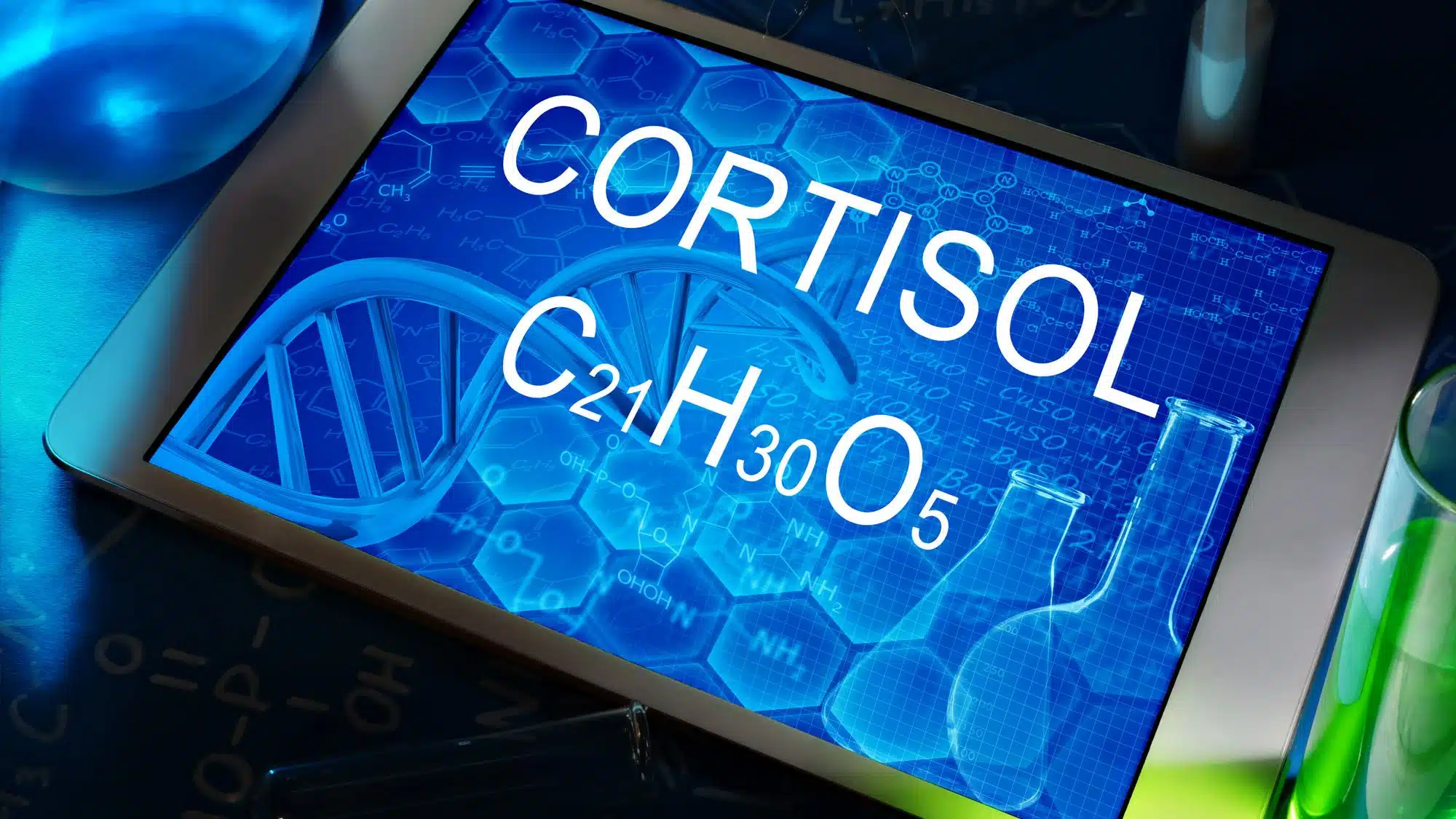 Tablet displaying cortisol chemical formula with DNA helix and lab tools