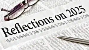 Newspaper headlined 'Reflections on 2025' with glasses and pen on newsprint