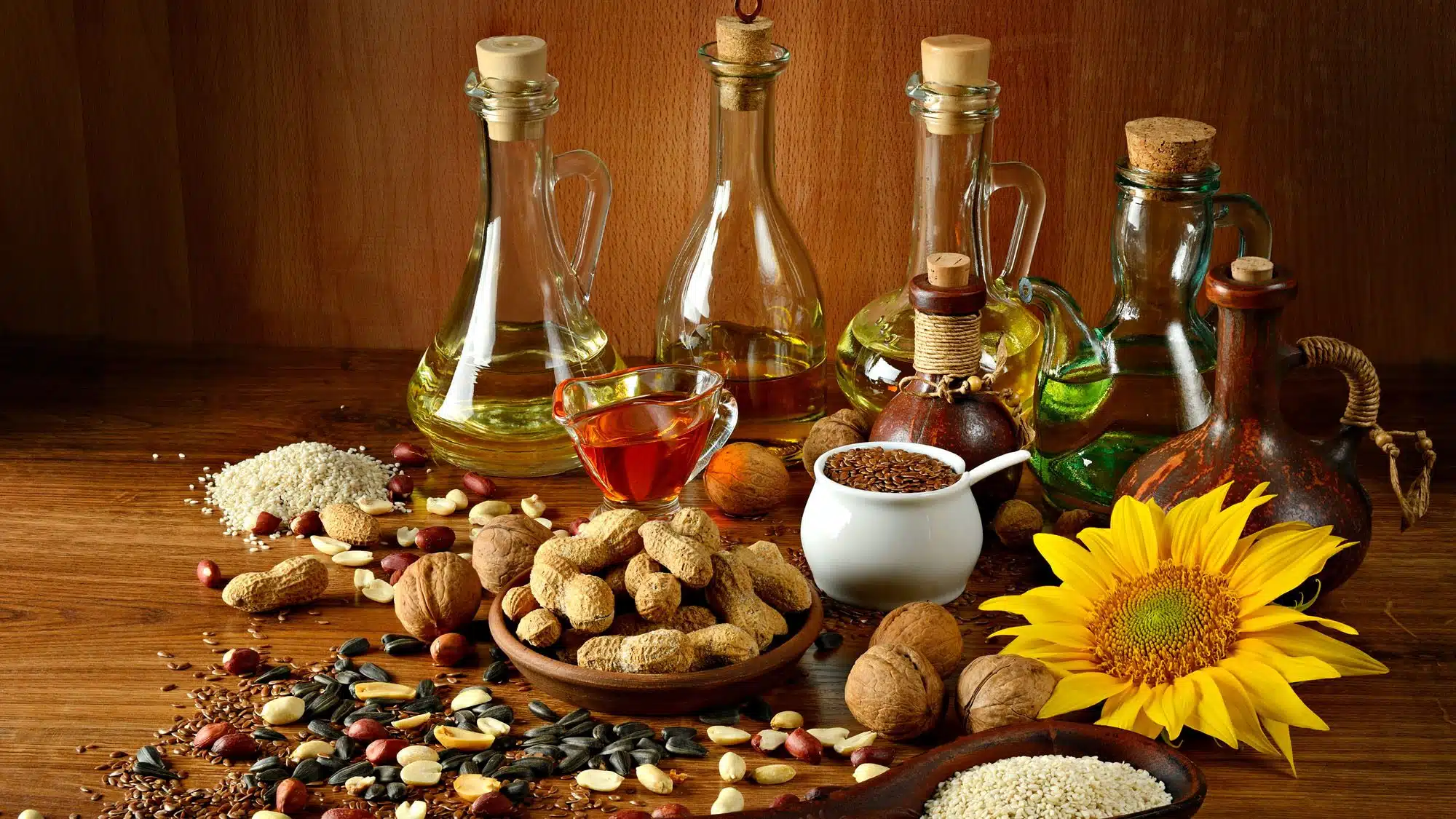 Assortment of nuts, oils, seeds, and sunflower on a wooden table