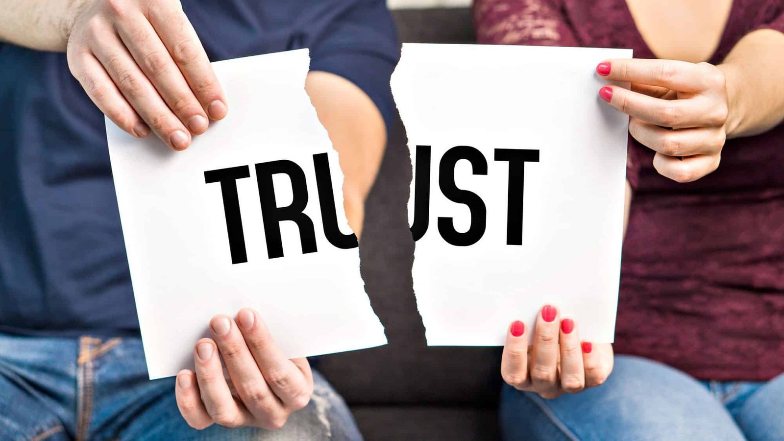 Two people tearing a paper with the word 'trust'