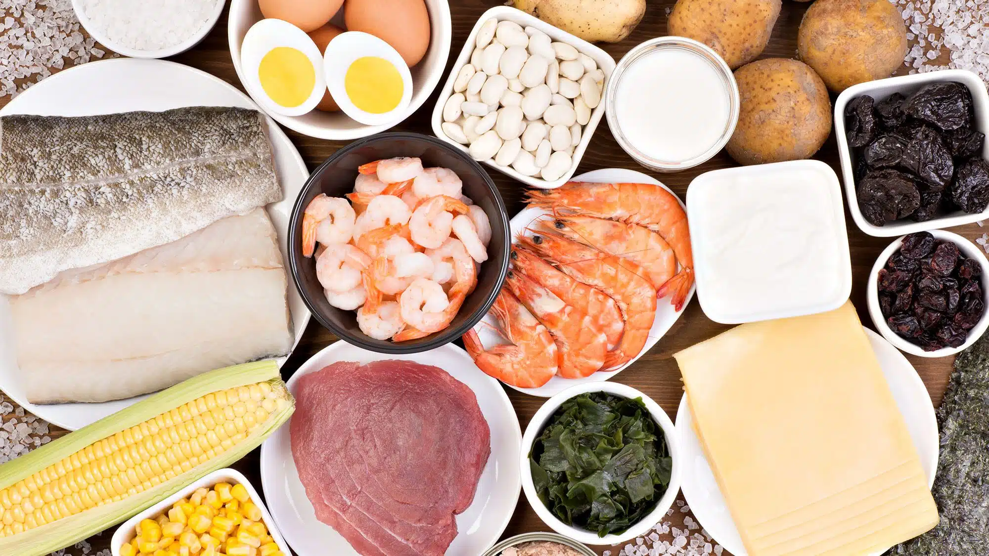 Assortment of high protein foods including fish, shrimp, eggs, and beans