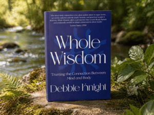 Whole Wisdom book by Debbie Knight on mind-body connection beside a stream
