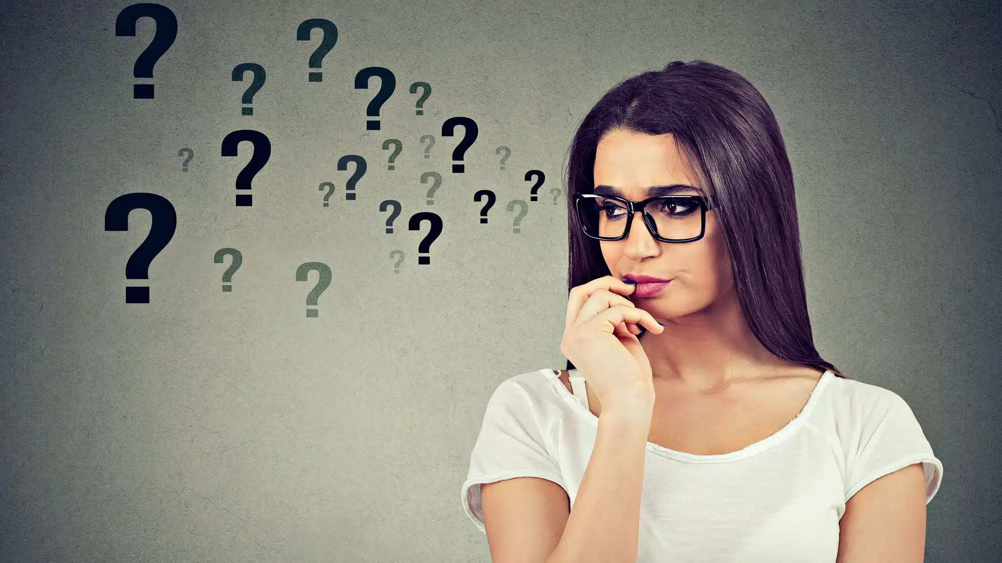 Thoughtful woman surrounded by question marks, contemplating ideas