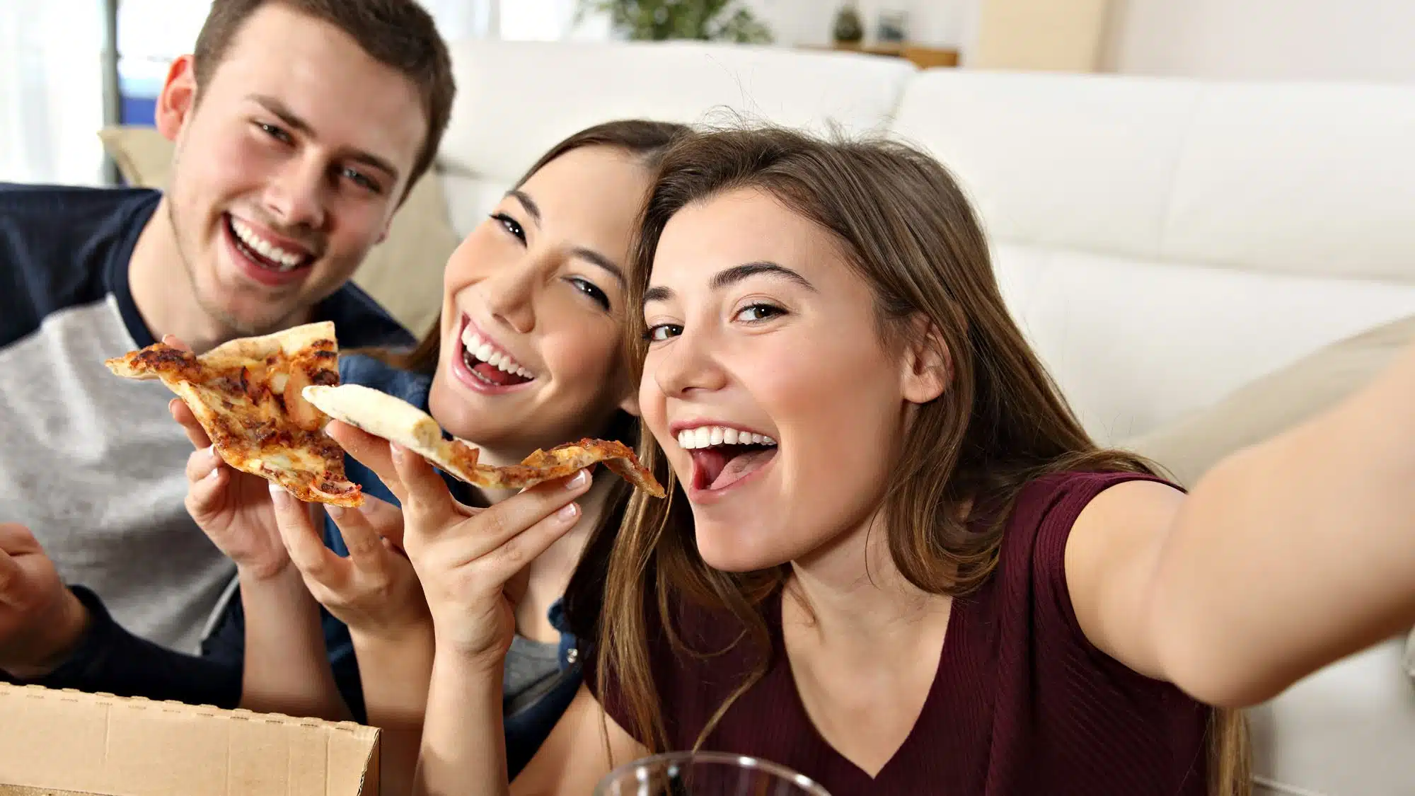 Friends enjoying pizza together while taking a selfie
