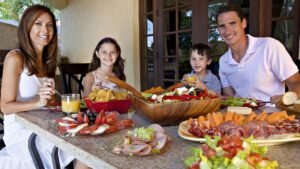 Family enjoying brunch with fresh produce and charcuterie outdoors
