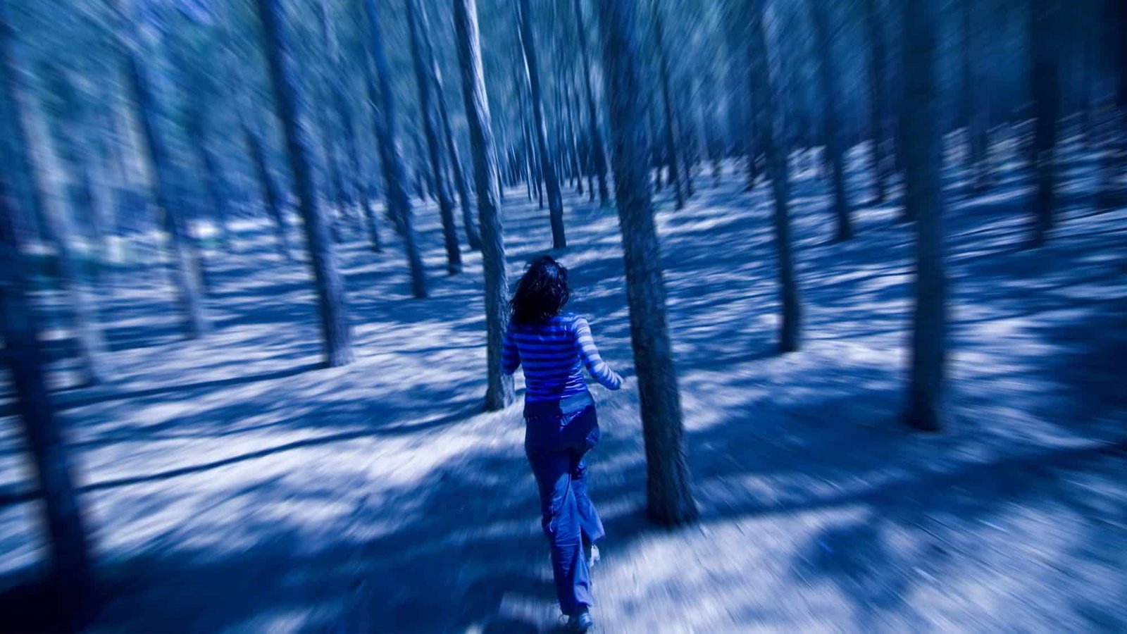 Woman running through a blurred forest in motion blur