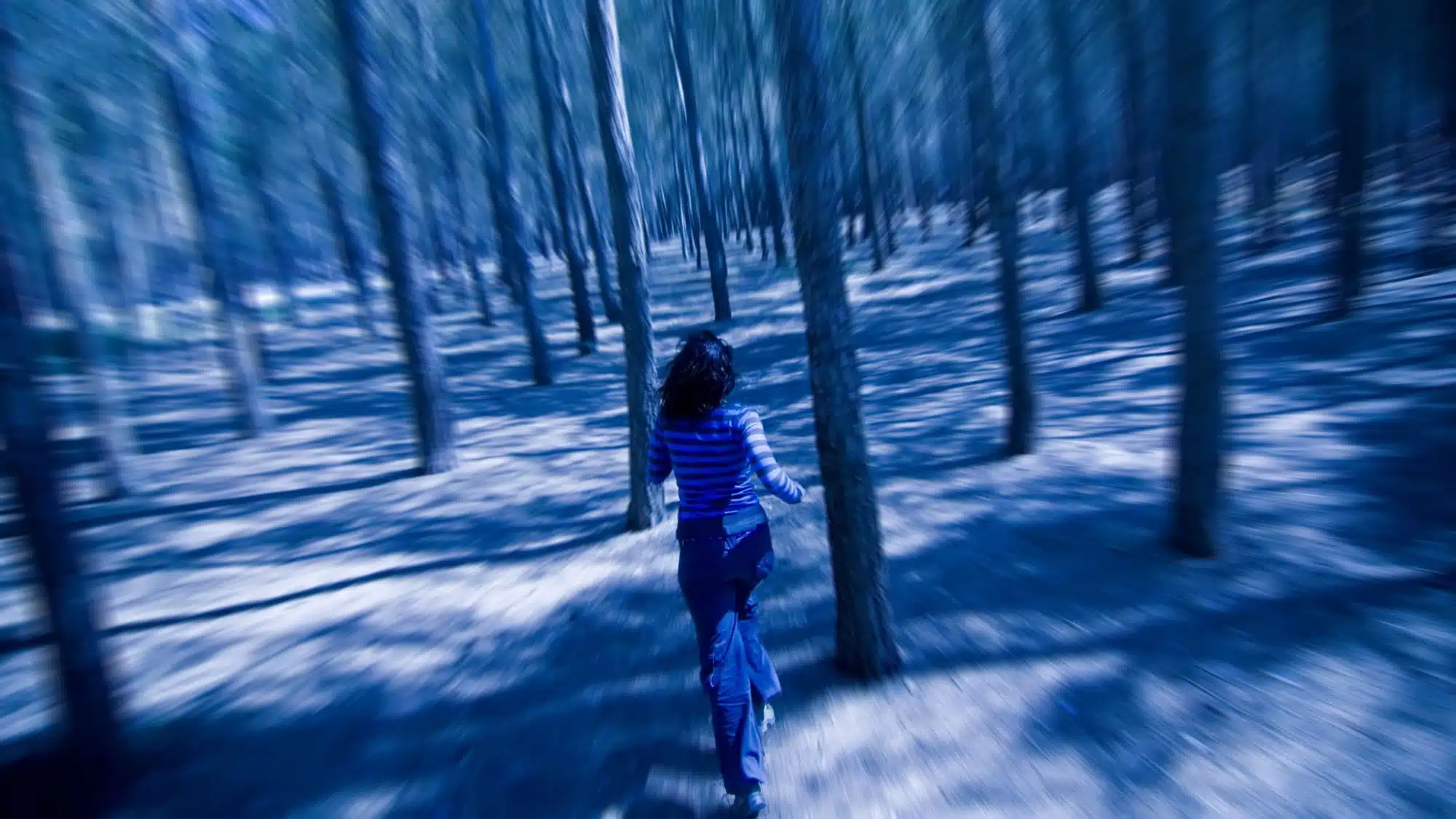 Woman running through a blurred forest in motion blur