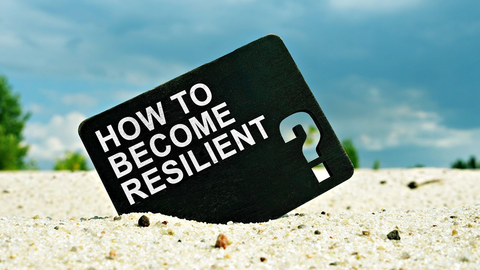 Sign in sand with 'How to Become Resilient' against a cloudy sky