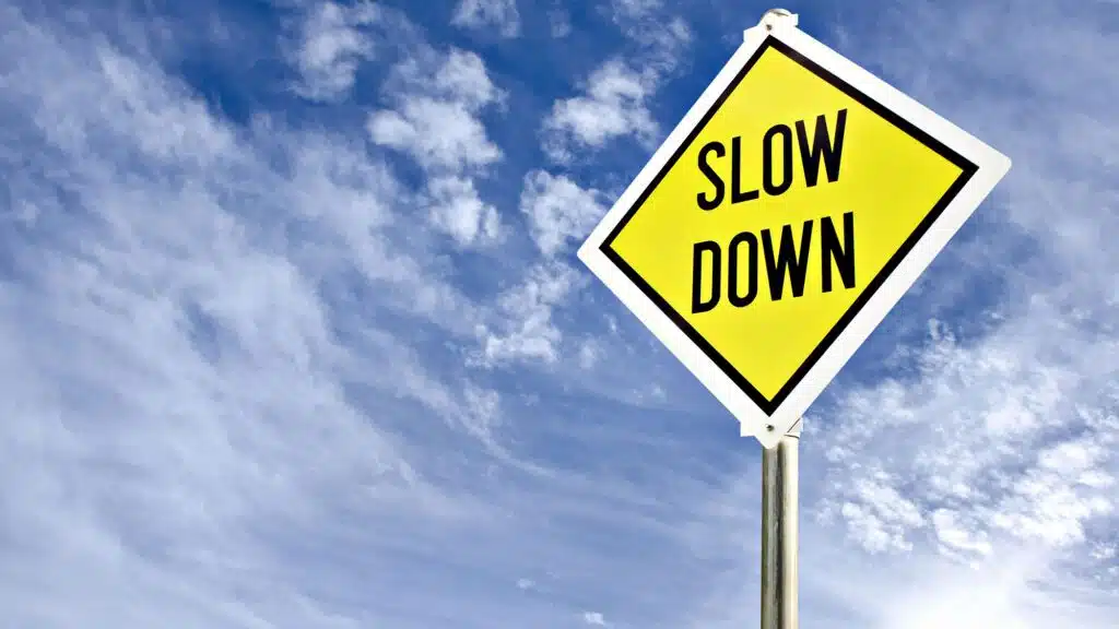 Yellow 'Slow Down' road sign against blue sky