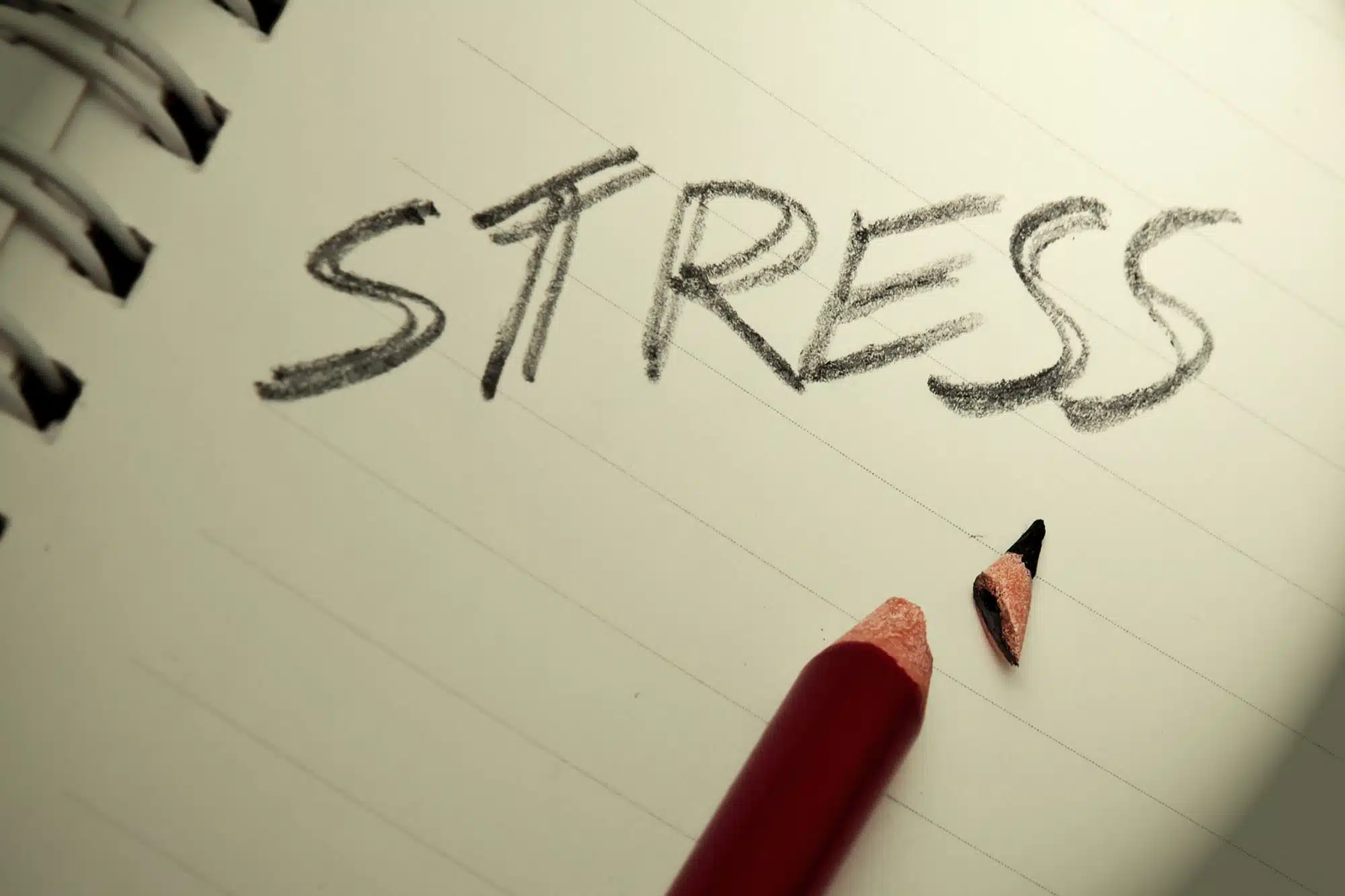 Stress concept with broken pencil next to the word stress on paper