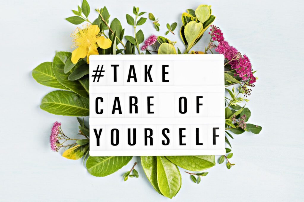 Take care of yourself message on lightbox surrounded by fresh flowers