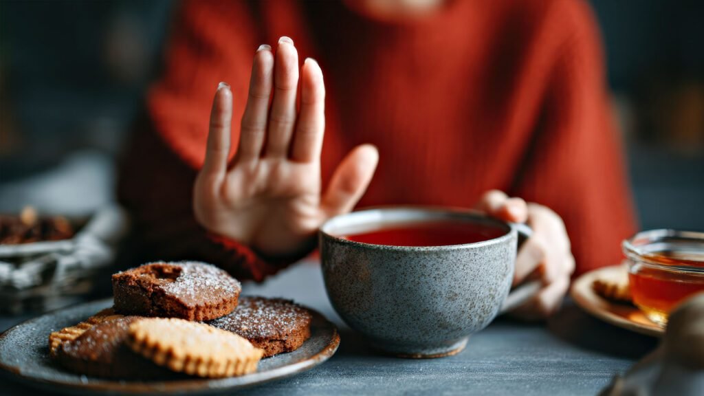 Person refusing sugary biscuits, holding herbal tea