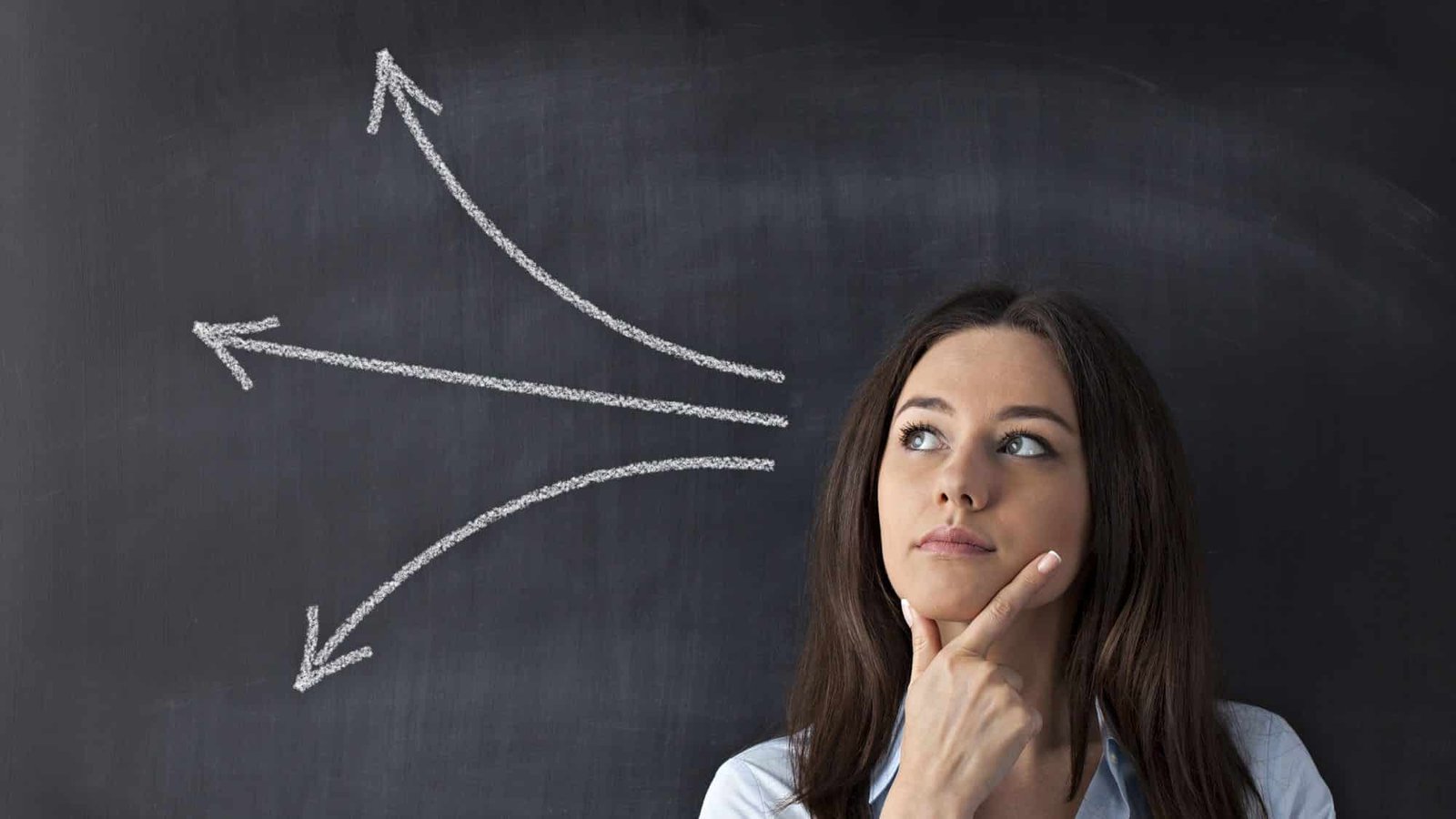 Thoughtful woman facing decision-making with diverging arrows on chalkboard