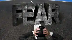 Person in suit facing large 'FEAR' word on road